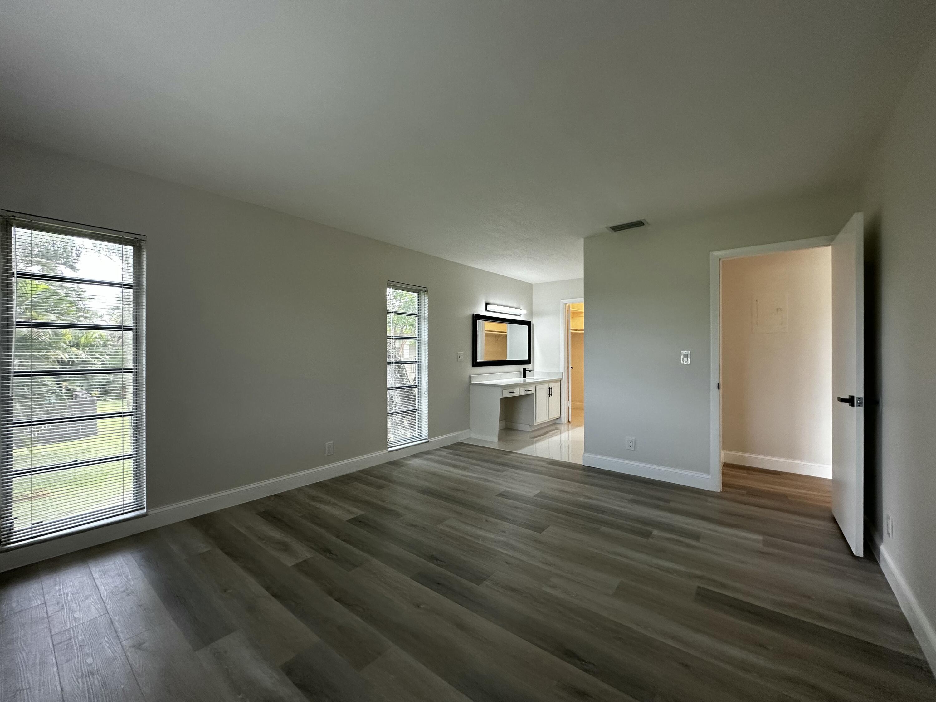 13682 Vía Flora, Unit H Delray Beach, FL 33484 - Photo 18 of 28 an empty room with wooden floor closet and windows
