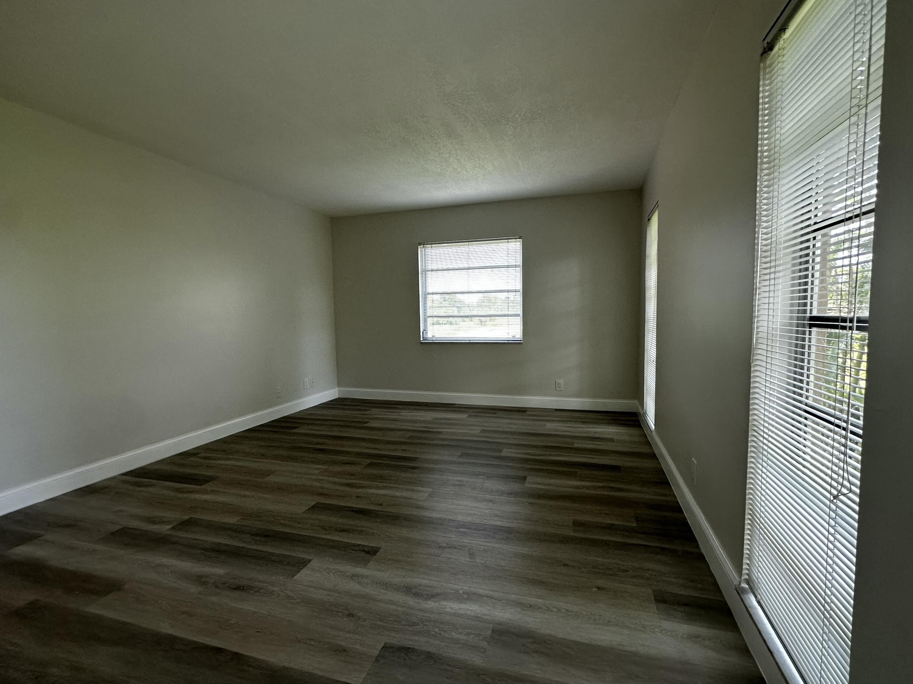 13682 Vía Flora, Unit H Delray Beach, FL 33484 - Photo 24 of 28 a view of an empty room with wooden floor and a window