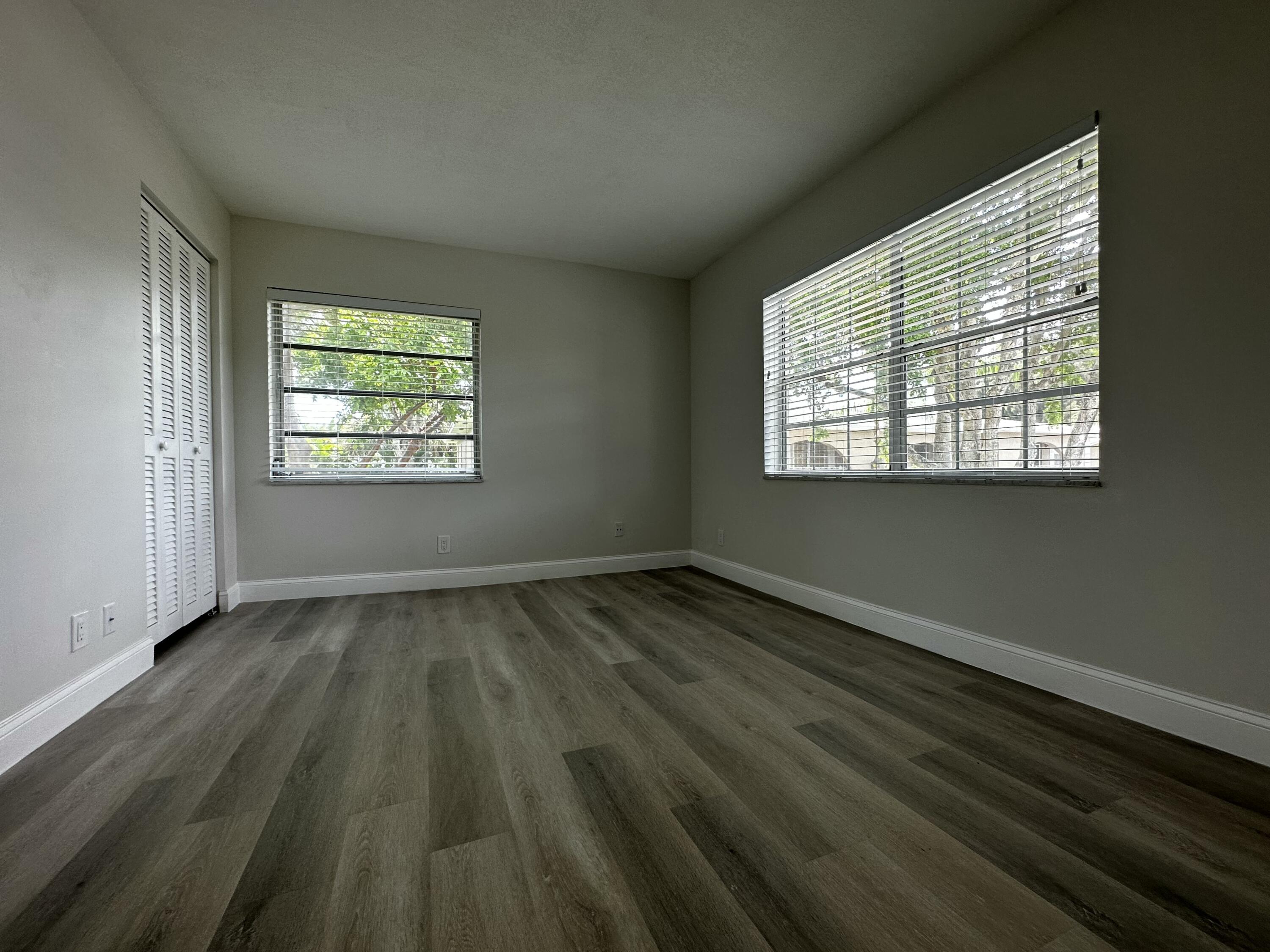 13682 Vía Flora, Unit H Delray Beach, FL 33484 - Photo 25 of 28 a view of an empty room with wooden floor and a window