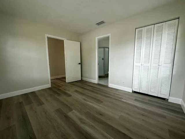 a view of an empty room with wooden floor and closet