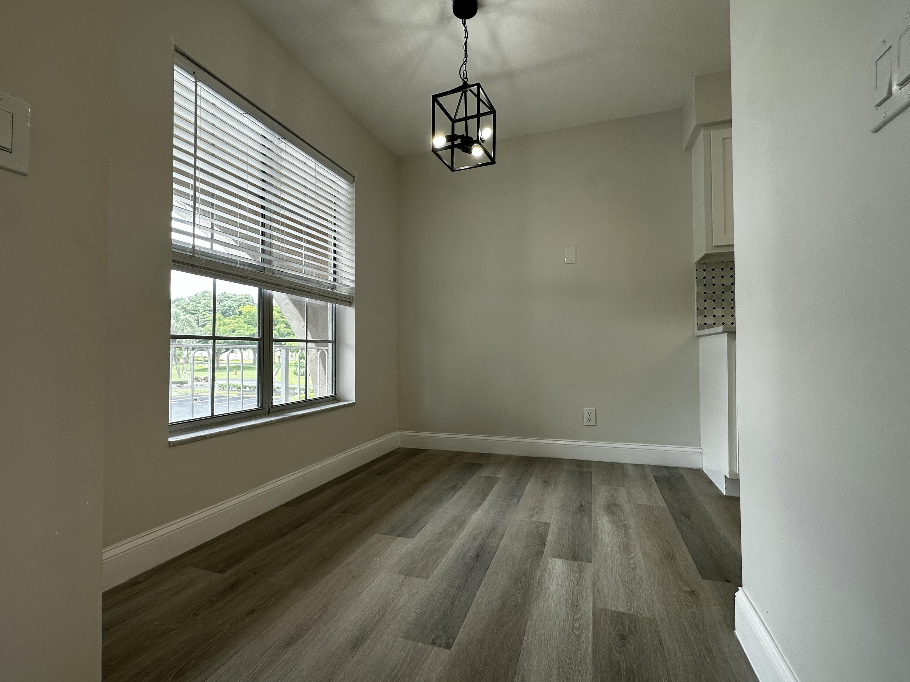 13682 Vía Flora, Unit H Delray Beach, FL 33484 - Photo 5 of 28 a view of a room with wooden floor and a window