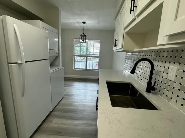 a kitchen with granite countertop a refrigerator a sink and wooden floor