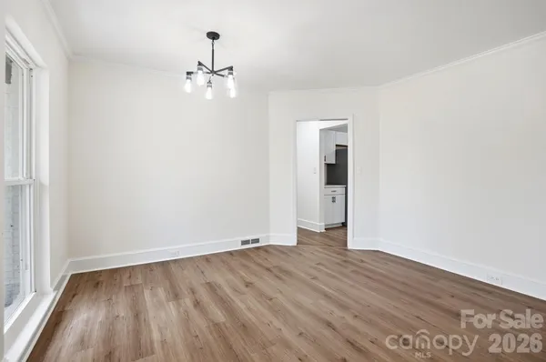 an empty room with wooden floor chandelier fan and windows