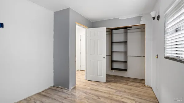 a view of an empty room with wooden floor and closet