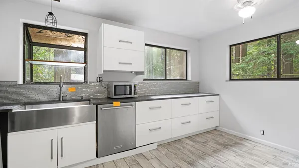a kitchen with stainless steel appliances granite countertop a sink window and cabinets