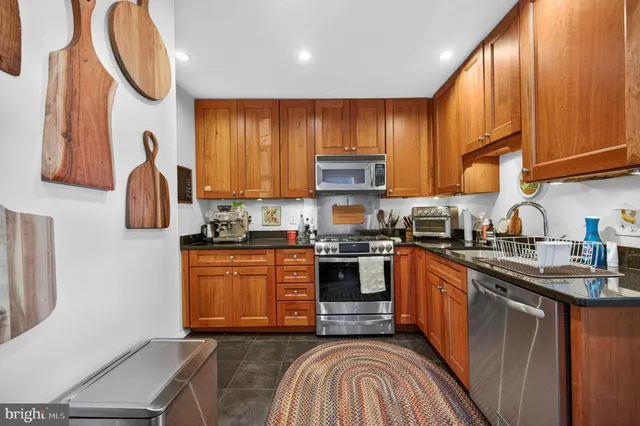 a kitchen with stainless steel appliances granite countertop wooden cabinets a stove top oven a sink and dishwasher