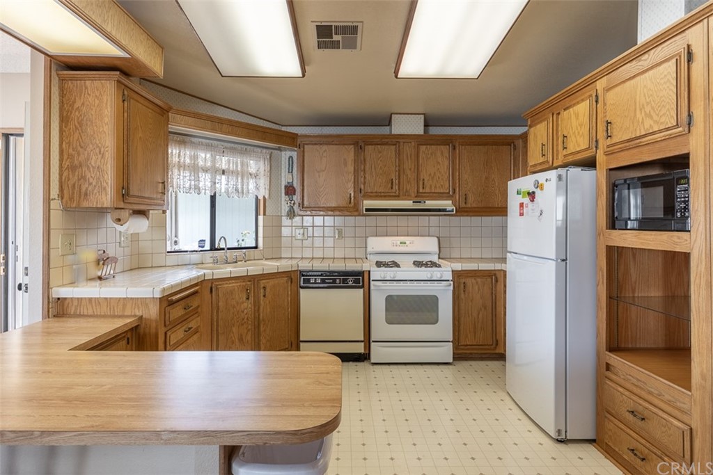 24600 Mountain Avenue, Unit 57 Hemet, CA 92544 - Photo 6 of 20 a kitchen with stainless steel appliances granite countertop a refrigerator sink stove microwave and cabinets