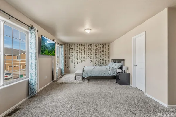 a bedroom with a bed couch and a large window