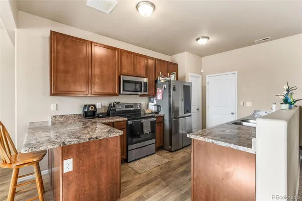 a kitchen with kitchen island granite countertop stainless steel appliances a stove refrigerator sink and microwave