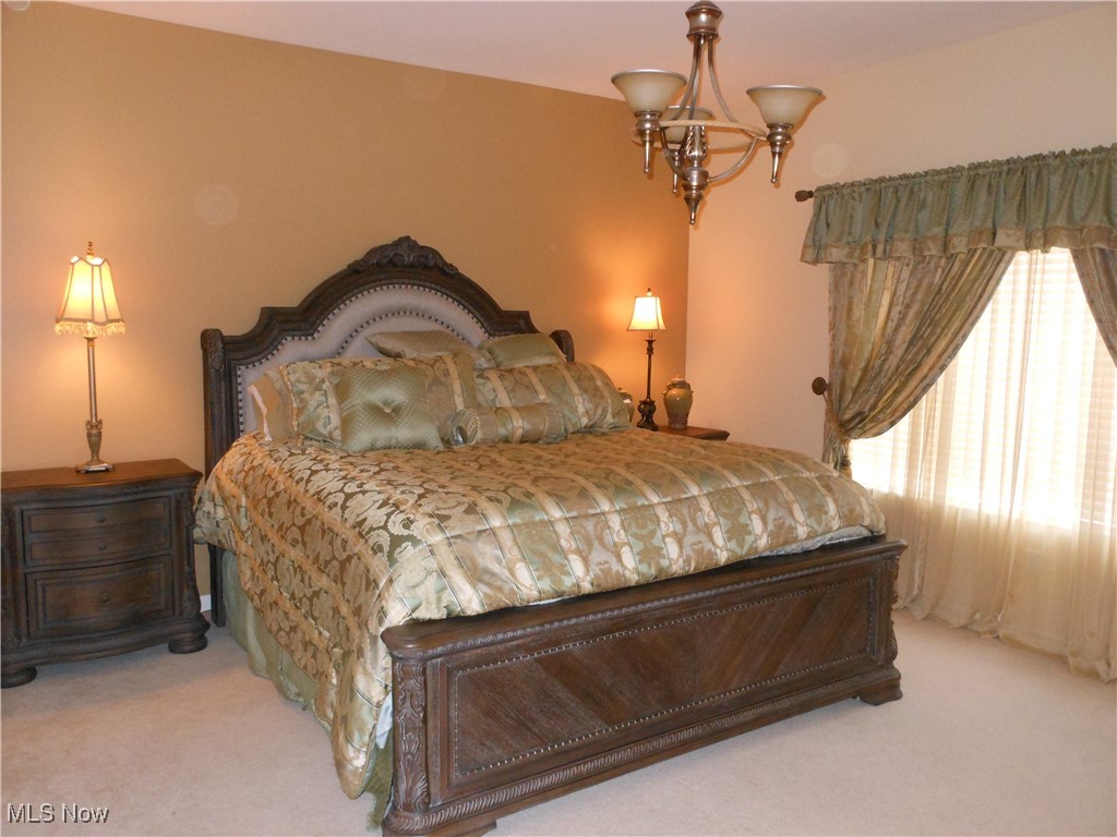 5645 Clingan Road, Unit 18A Struthers, OH 44471 - Photo 22 of 38 Master Bedroom with light colored carpet and a chandelier. The bed is a king size.
