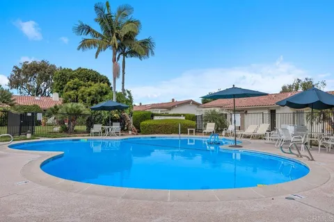 a view of a swimming pool with lawn chairs under an umbrella