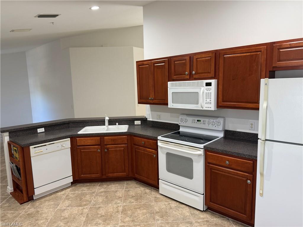 1345 Henley Street, Unit 705 Naples, FL 34105 - Photo 5 of 16 a kitchen with wood cabinets and white appliances