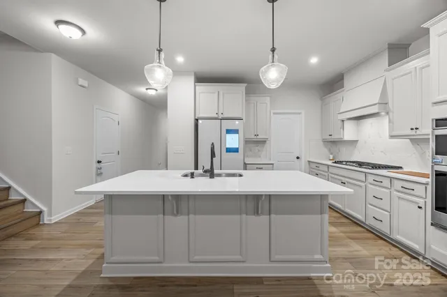 a large kitchen with granite countertop a stove a sink a island and a cabinets