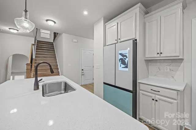 a kitchen with stainless steel appliances granite countertop a refrigerator a sink and white countertops with granite countertops