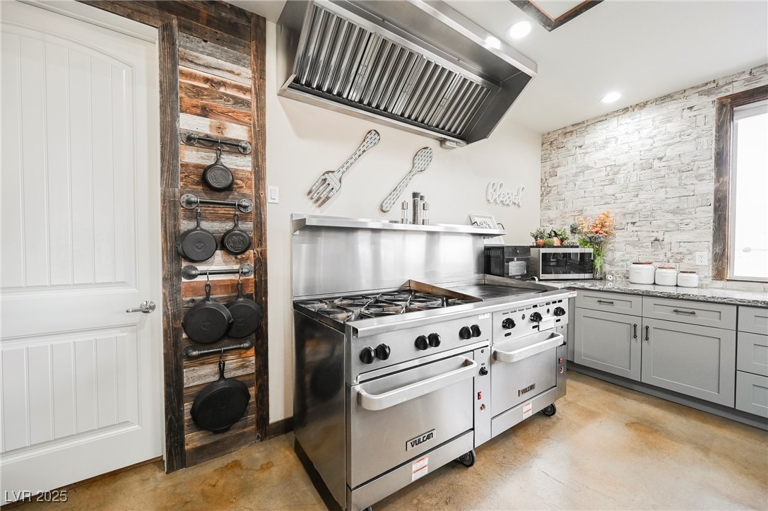 6510 Sunset Drive Caliente, NV 89008 - Photo 26 of 84 Kitchen with gray cabinetry, ventilation hood, stainless steel appliances, light stone countertops, and concrete floors