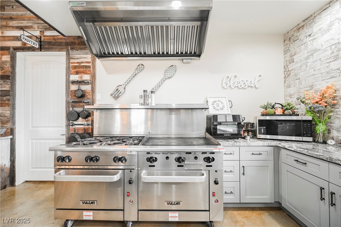6510 Sunset Drive Caliente, NV 89008 - Photo 56 of 84 Kitchen with exhaust hood, appliances with stainless steel finishes, light stone counters, and finished concrete floors