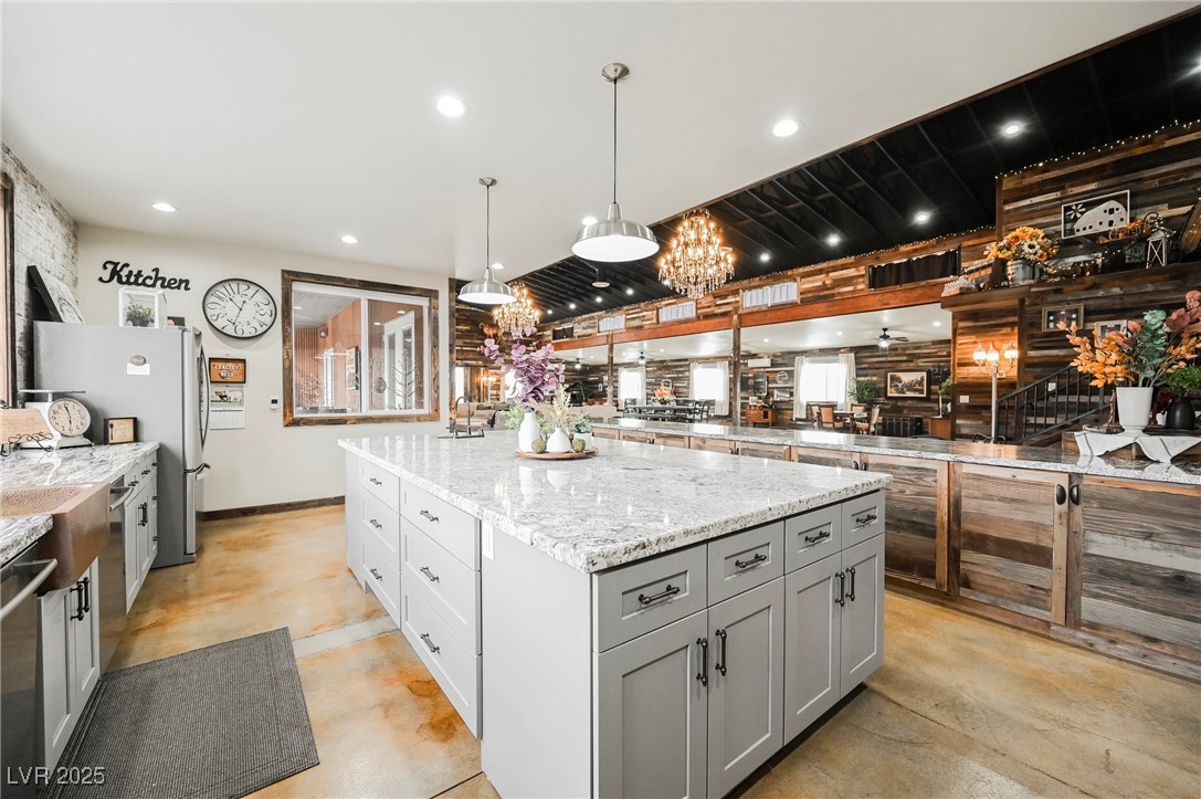 6510 Sunset Drive Caliente, NV 89008 - Photo 7 of 84 Kitchen with gray cabinetry, finished concrete flooring, light stone countertops, a center island, and appliances with stainless steel finishes