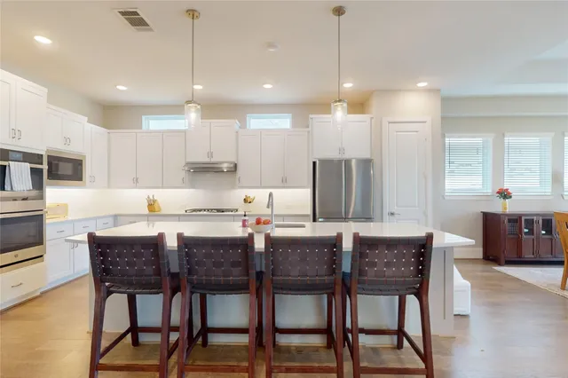 a kitchen with stainless steel appliances kitchen island granite countertop a dining table chairs and sink