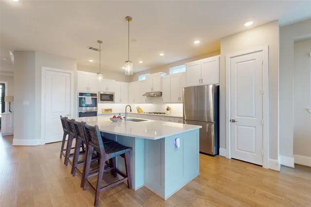 a kitchen with stainless steel appliances kitchen island granite countertop a table chairs refrigerator and microwave