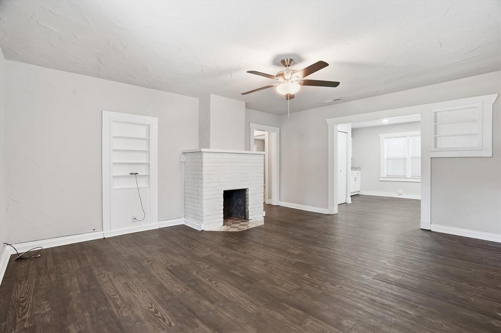 711 Roberts Cut Off Road River Oaks, TX 76114 - Photo 7 of 21 an empty room with wooden floor fireplace and windows