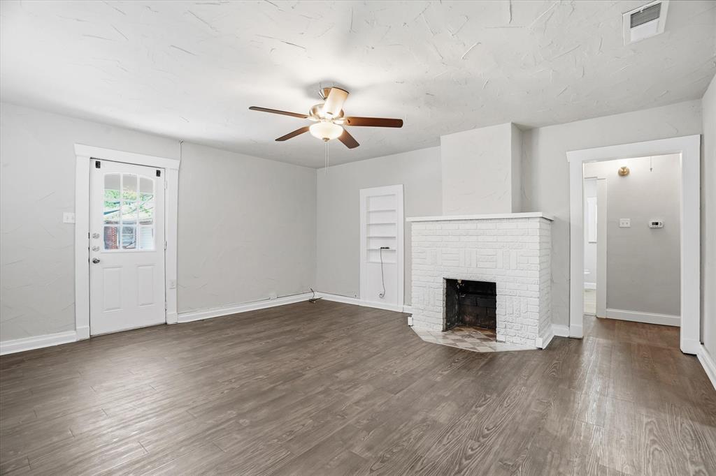 711 Roberts Cut Off Road River Oaks, TX 76114 - Photo 8 of 21 an empty room with wooden floor fireplace and fan