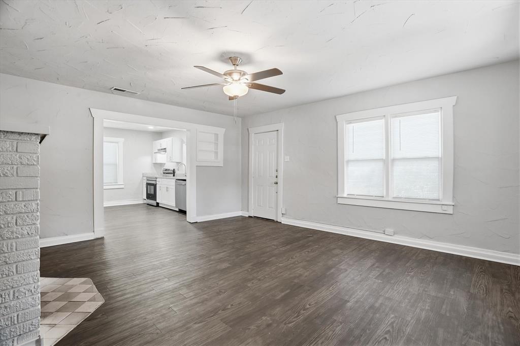 711 Roberts Cut Off Road River Oaks, TX 76114 - Photo 9 of 21 an empty room with wooden floor chandelier fan and windows