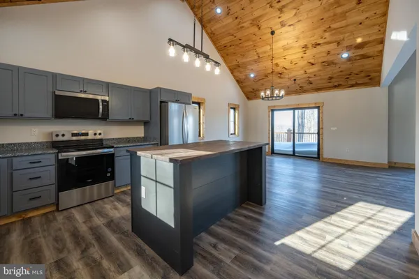 a view of an entryway with wooden floor leading to a furnished livingroom and windows