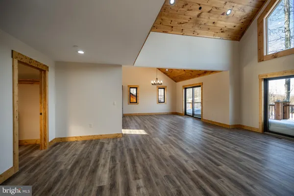 a view of an empty room with wooden floor and ceiling fan