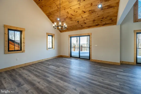an empty room with wooden floor chandelier and windows