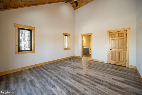 a view of an empty room with wooden floor and ceiling fan