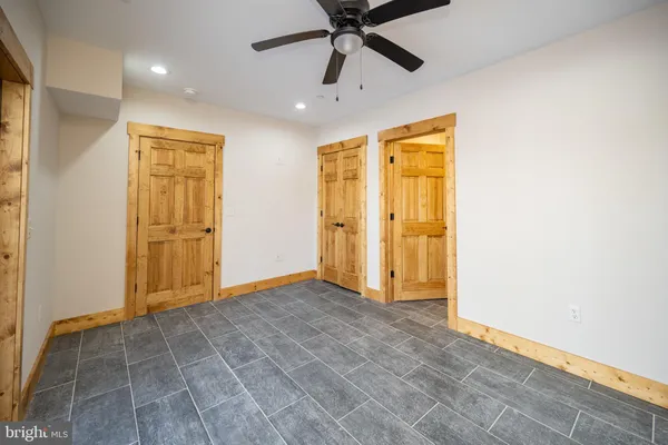 an empty room with wooden floor chandelier and windows