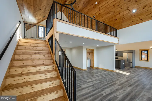 a view of an entryway with wooden floor leading to a furnished livingroom and windows