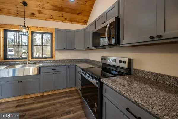 a kitchen with granite countertop cabinets stainless steel appliances a sink and a window
