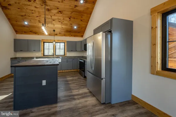 a large kitchen with stainless steel appliances granite countertop a large stove a sink dishwasher and a microwave oven with wooden floor