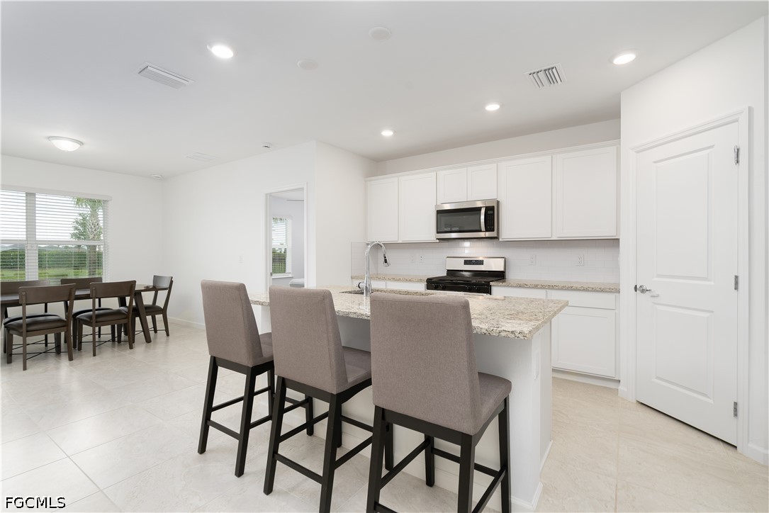 42428 Cascade Drive Punta Gorda, FL 33982 - Photo 4 of 47 a kitchen with stainless steel appliances granite countertop a stove a refrigerator a microwave a dining table and chairs