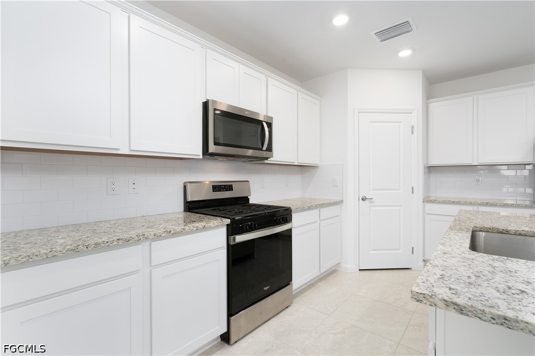 42428 Cascade Drive Punta Gorda, FL 33982 - Photo 6 of 47 a kitchen with granite countertop white cabinets and stainless steel appliances