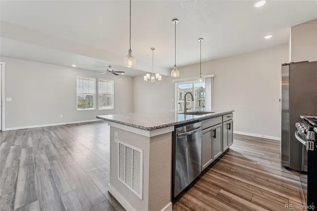 a kitchen with stainless steel appliances granite countertop a sink a stove and a wooden floors