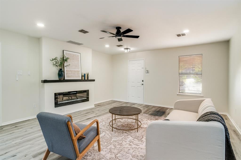 Living area with a glass covered fireplace, wood finished floors, a ceiling fan, and recessed lighting
