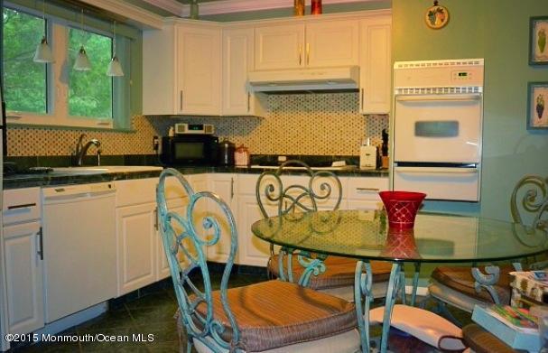371 Aldrich Road Howell, NJ 07731 - Photo 3 of 15 a kitchen with stainless steel appliances granite countertop a table chairs in it and wooden floors