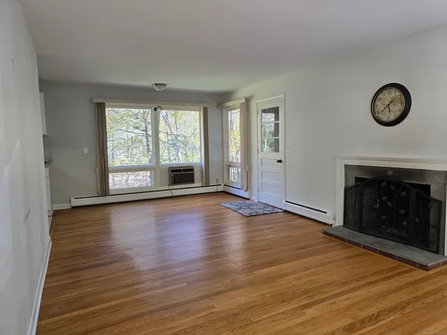 an empty room with wooden floor a fireplace and windows