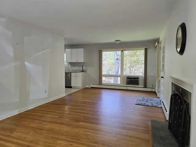 a view of empty room with a fireplace and wooden floor