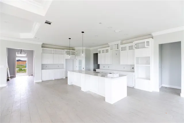 a large white kitchen with cabinets and a wooden floor