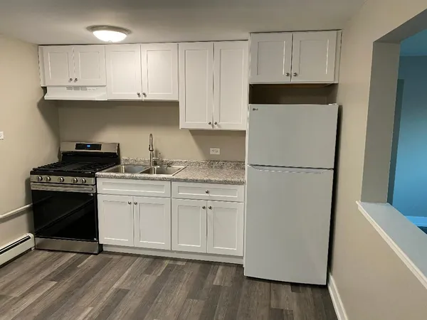 a kitchen with granite countertop white cabinets and refrigerator