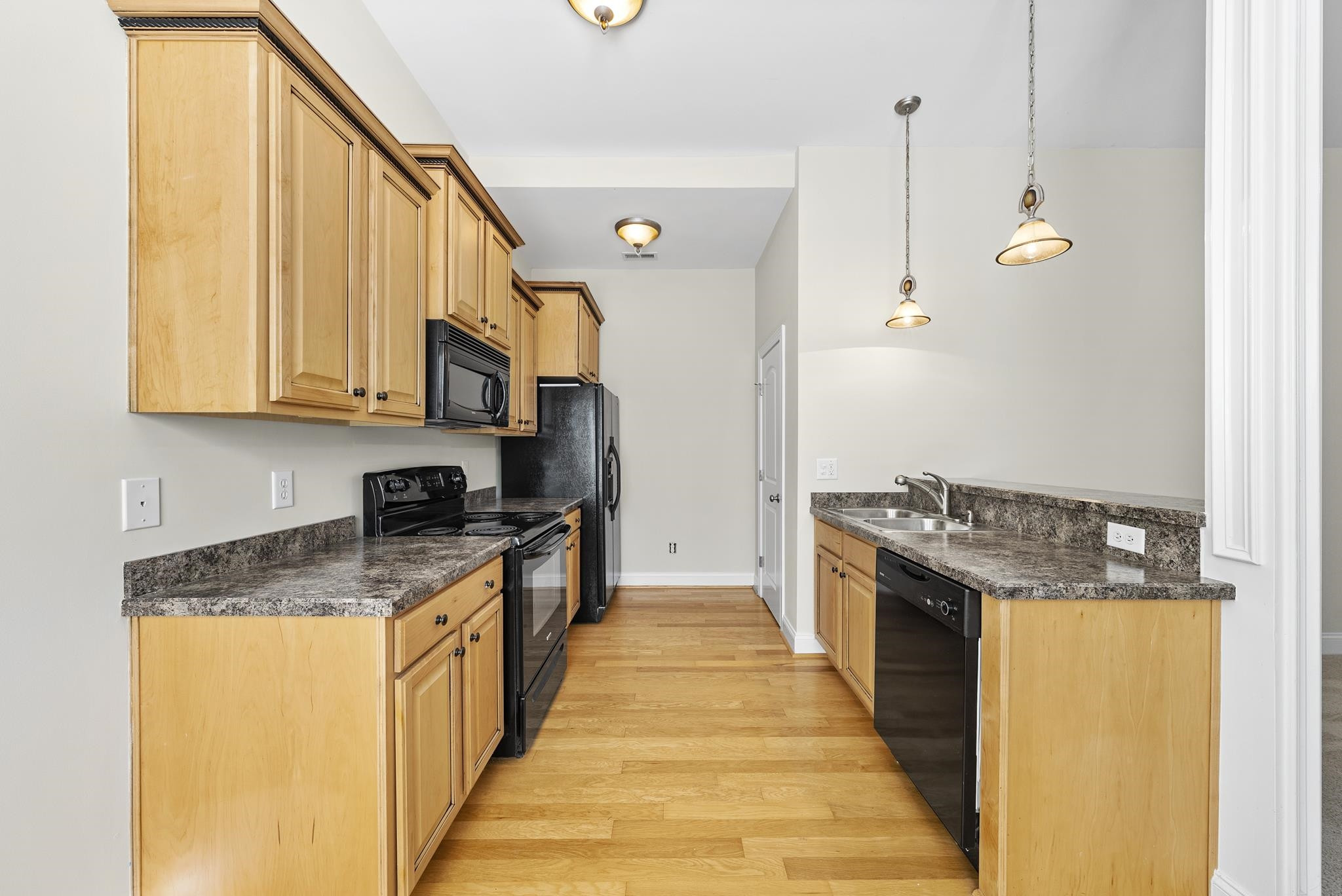 7357 Newport Avenue Raleigh, NC 27613 - Photo 29 of 44 a kitchen with granite countertop a sink a stove top oven and cabinetry