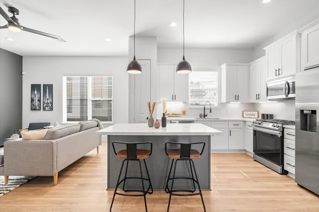 a kitchen with stainless steel appliances granite countertop a stove a sink dishwasher a refrigerator and white cabinets with wooden floor