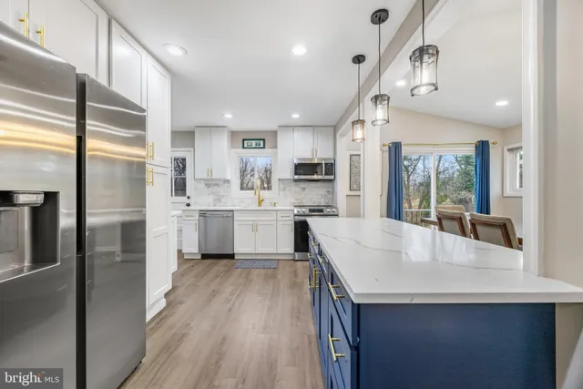 a kitchen with stainless steel appliances granite countertop a sink a stove a refrigerator and island with wooden floor