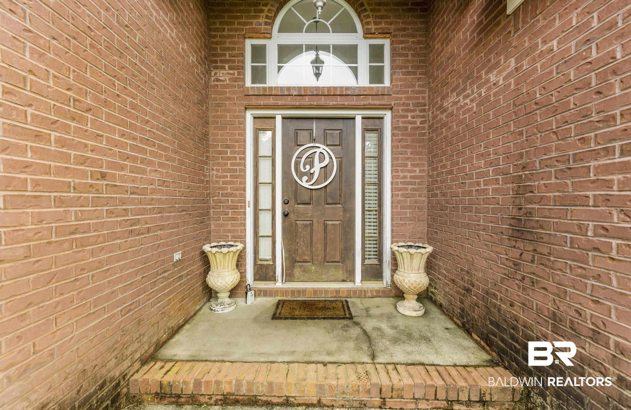 35814 Delvan Lane Bay Minette, AL 36507 - Photo 50 of 53 Brick exterior featuring a wood-paneled entry door with transom window and sidelights