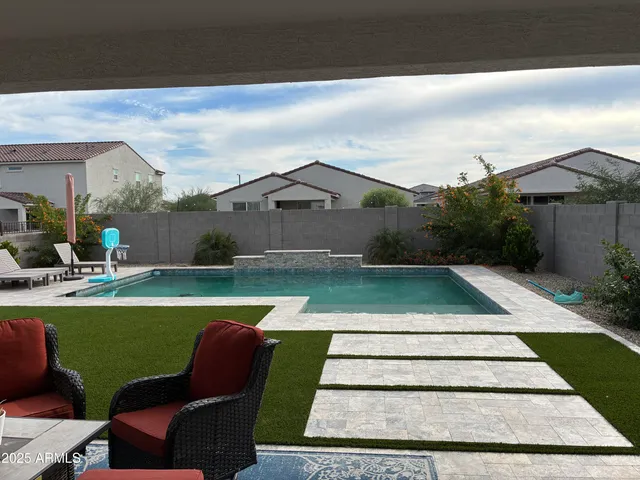 a view of swimming pool with lawn chairs and plants