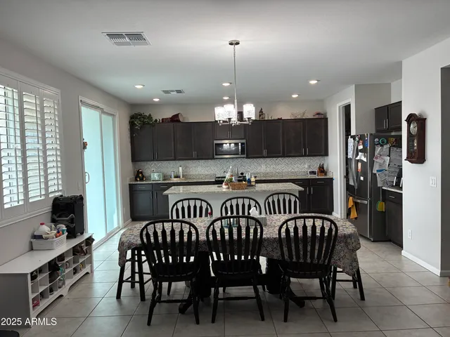a kitchen with a dining table chairs and refrigerator