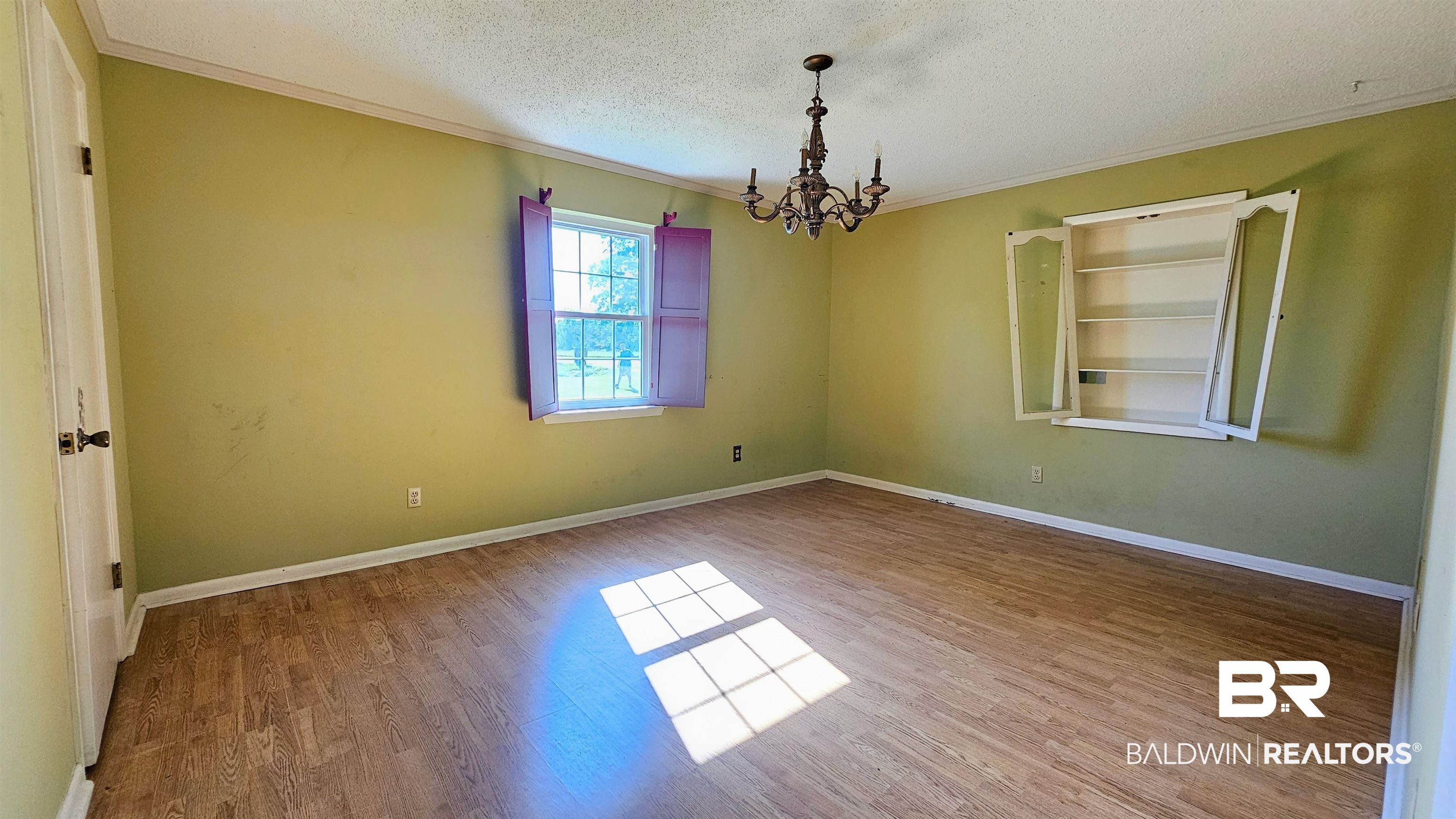 18824 Highway 41 Brewton, AL 36426 - Photo 26 of 40 Spacious room featuring wood-finish flooring, a window with exterior views, interior purple shutters, a ceiling-mounted chandelier, and a built-in wall cabinet with shelving
